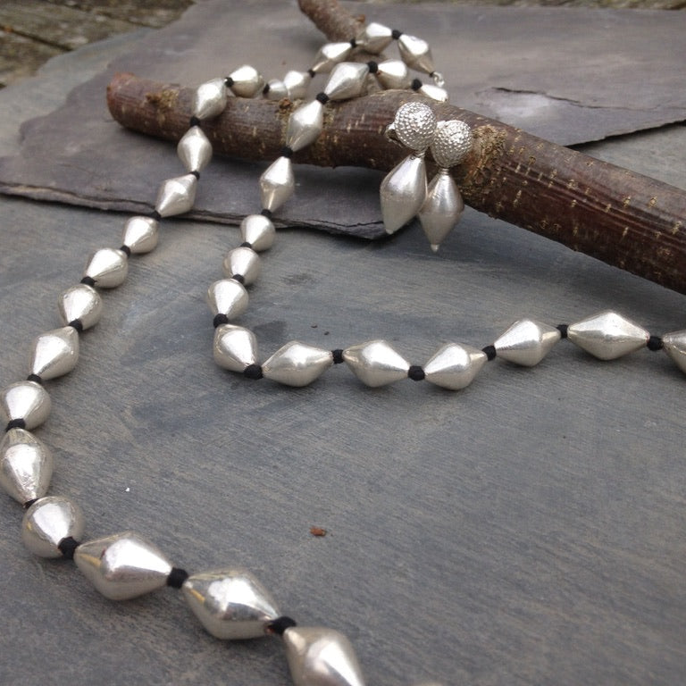 Silver beaded necklace on a stone surface