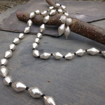 Silver beaded necklace on a stone surface